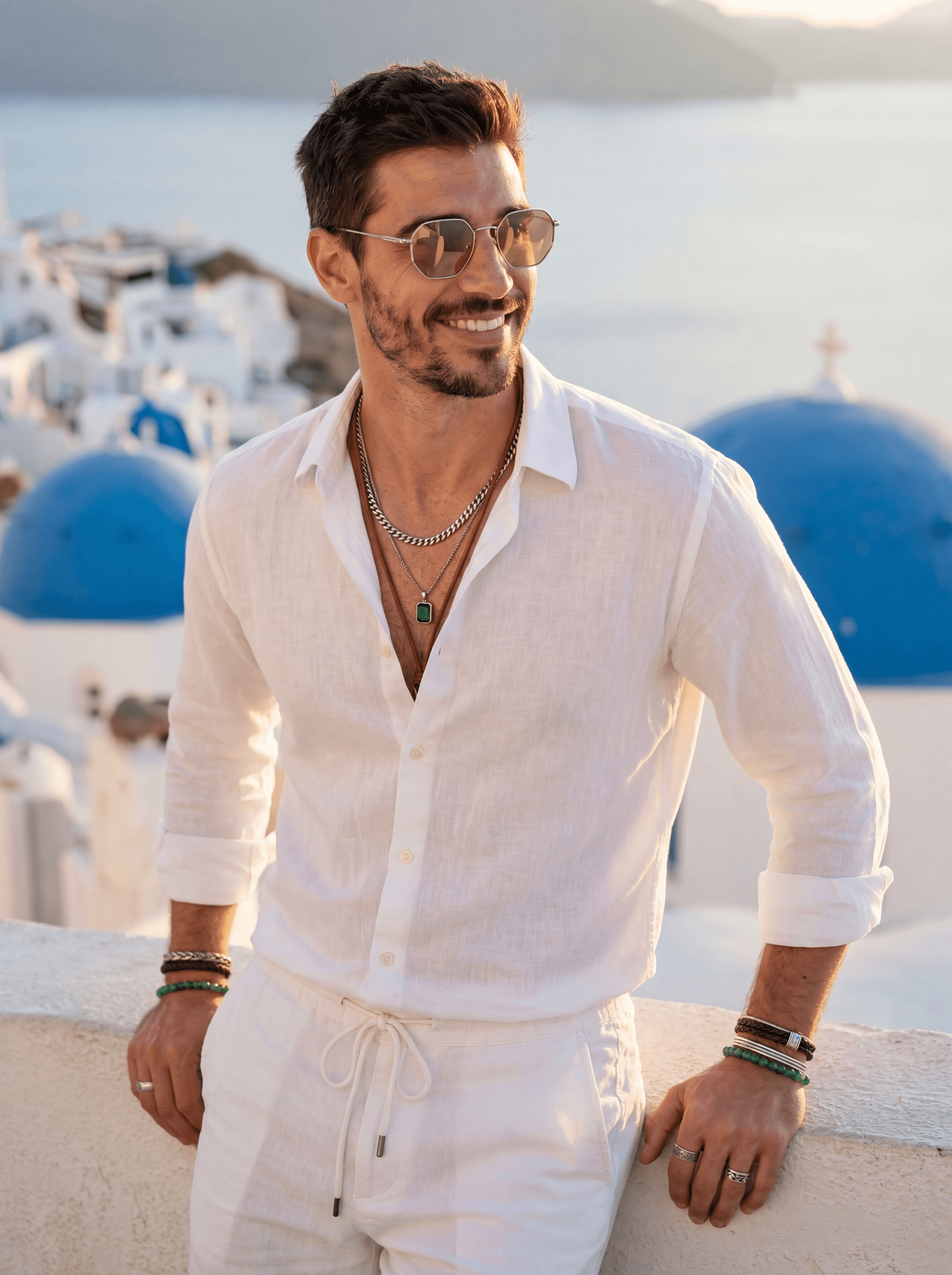 Example: man in white linen set leaning on Santorini parapet at golden hour