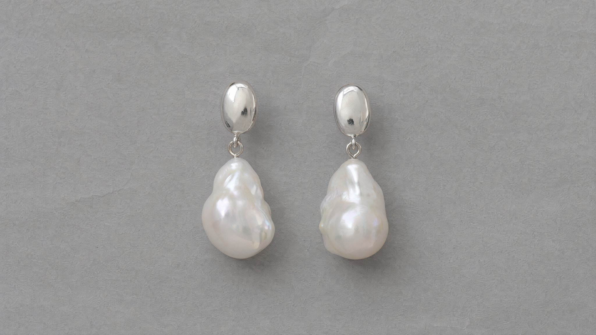 Pendientes de plata con perlas barrocas blancas sobre papel gris, generados con IA