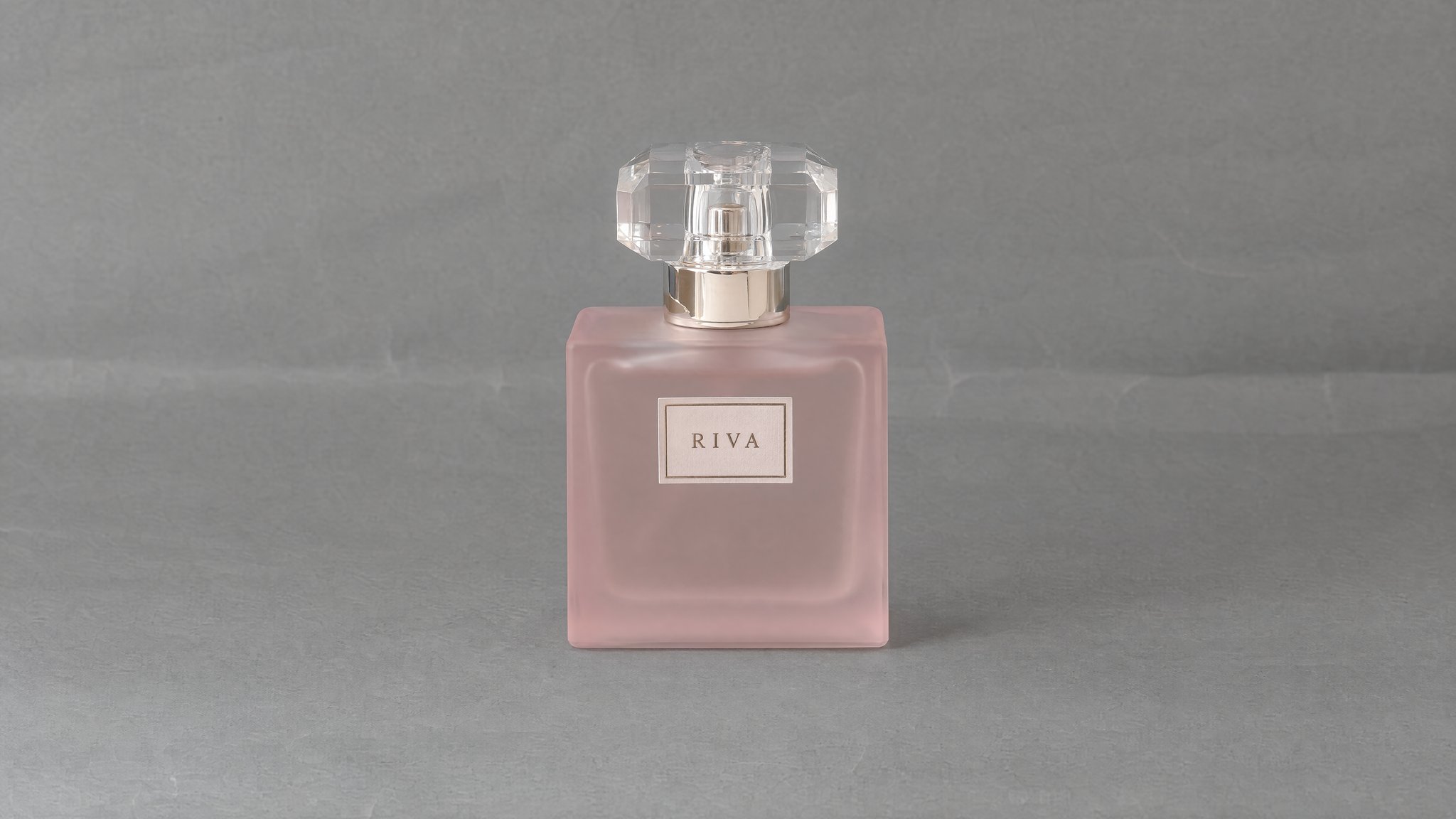 Frasco cuadrado RIVA de vidrio rosa esmerilado con tapón transparente facetado sobre papel gris, generado con IA