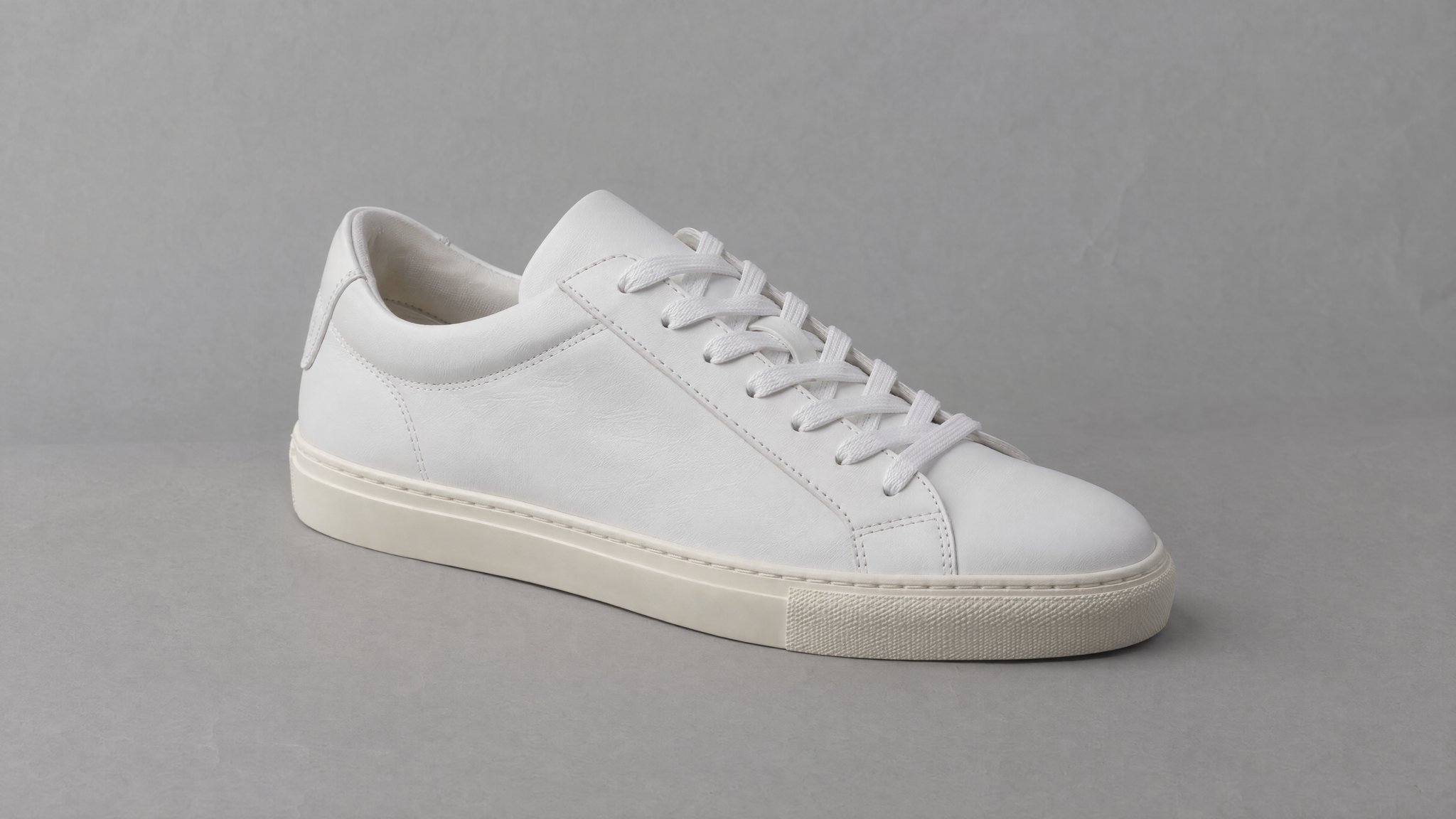 Unbranded white leather sneaker on gray paper, generated with AI