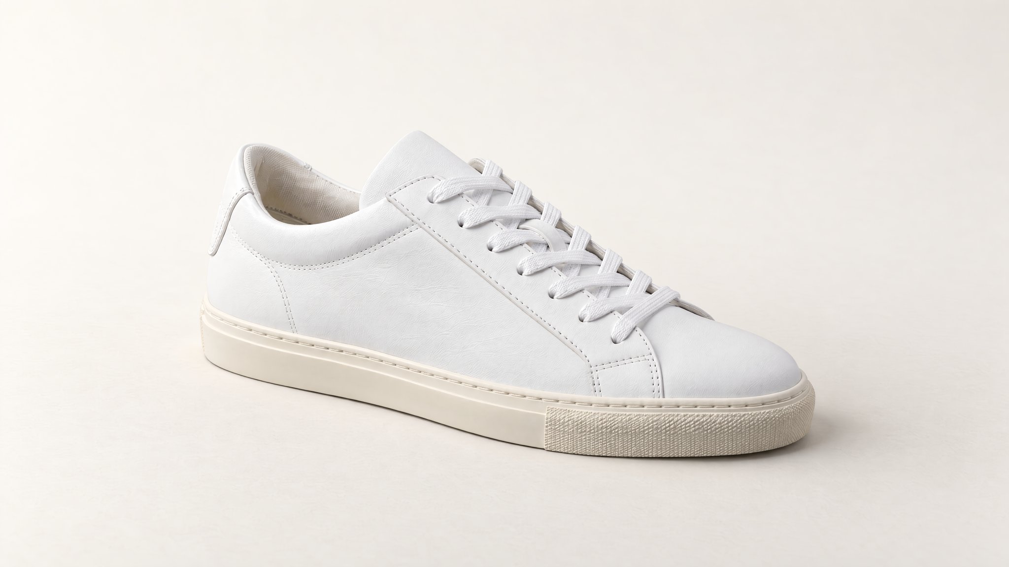 White leather sneaker with a cream sole against an off-white studio background