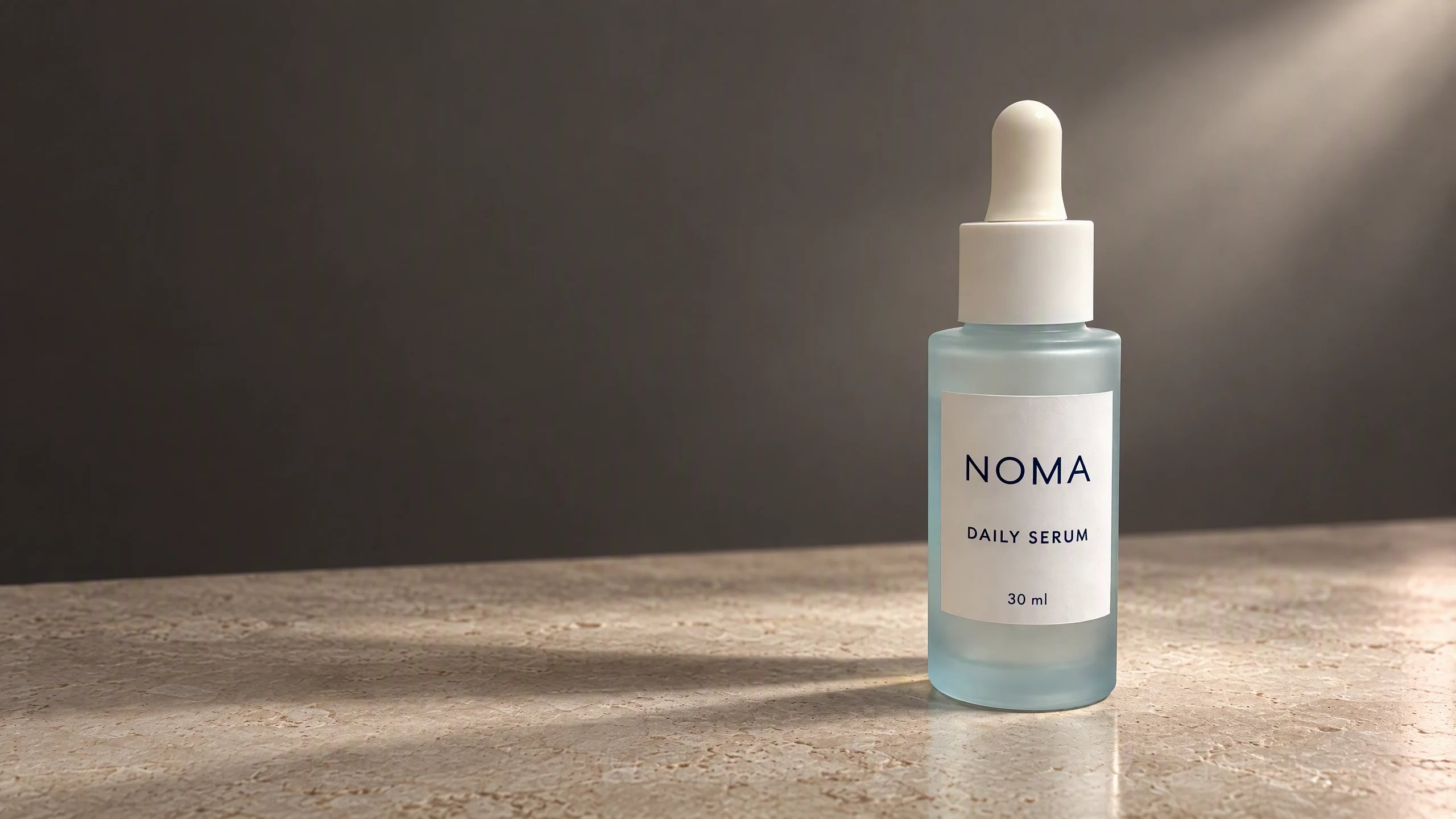NOMA serum transformed in HummingBytes into a neutral studio campaign on ivory stone against a charcoal background