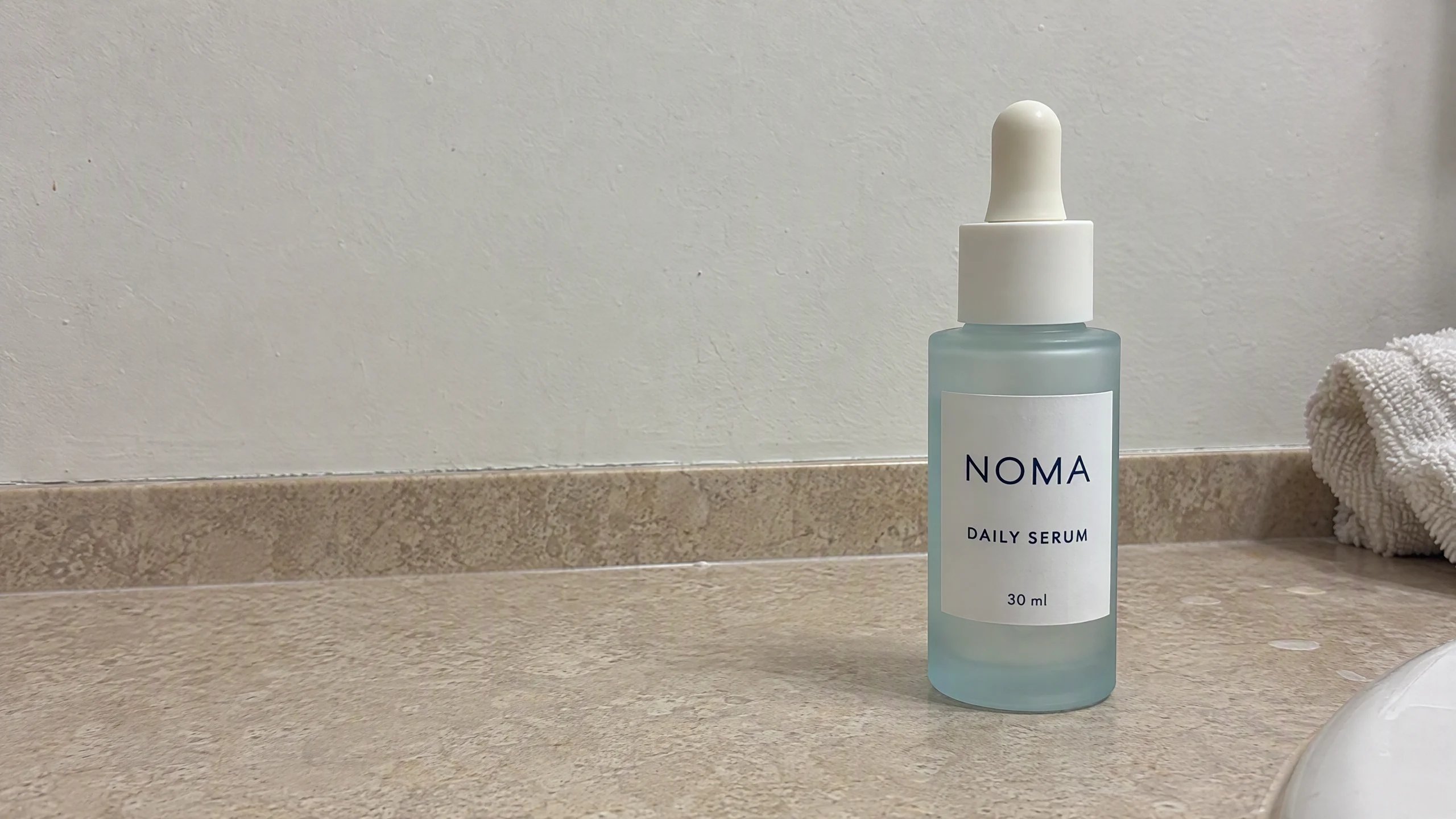 AI-generated NOMA serum reference in a casual phone-photo style on a bathroom counter