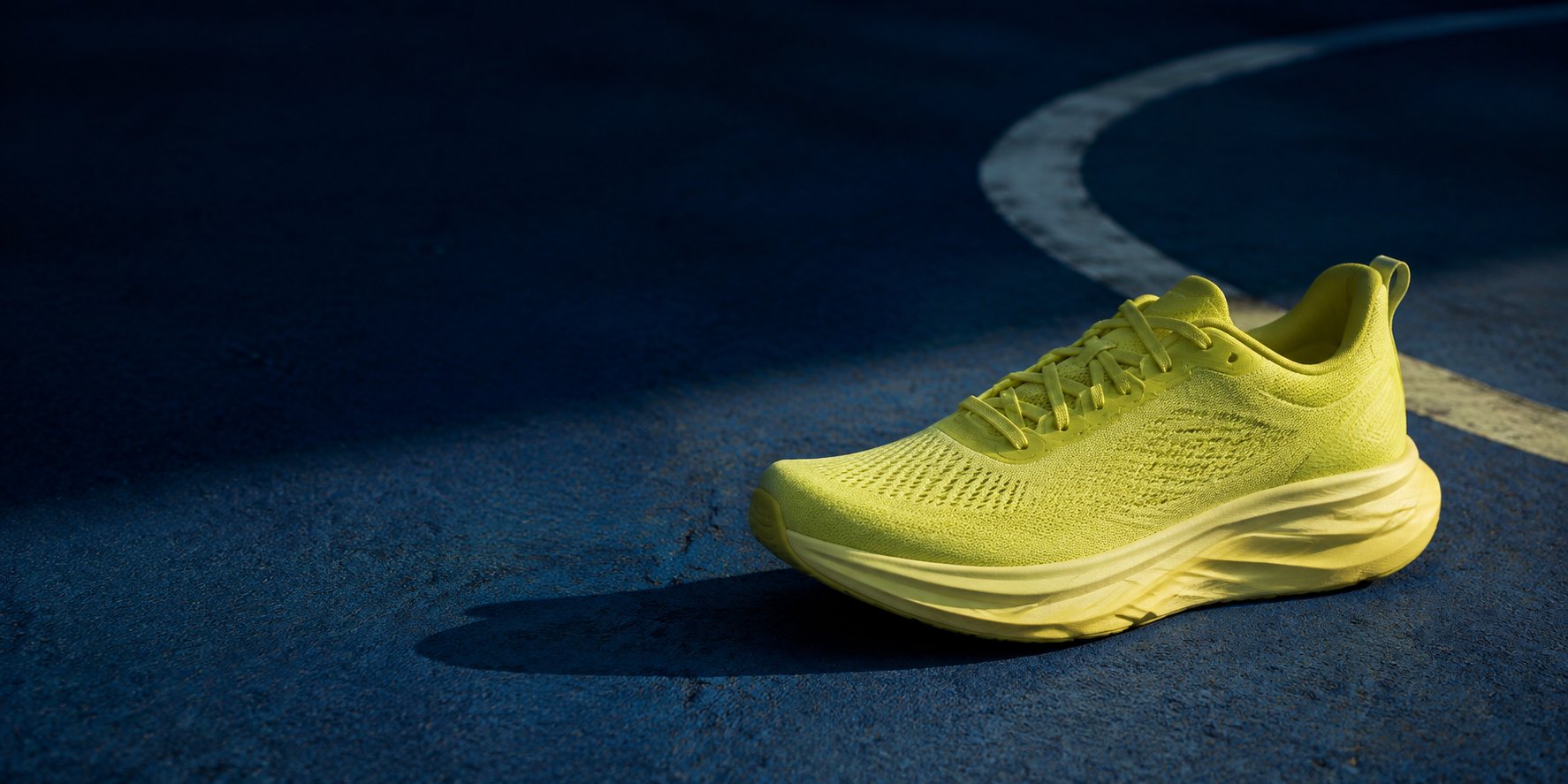 Una zapatilla de running verde lima sobre una cancha azul con luz de la tarde